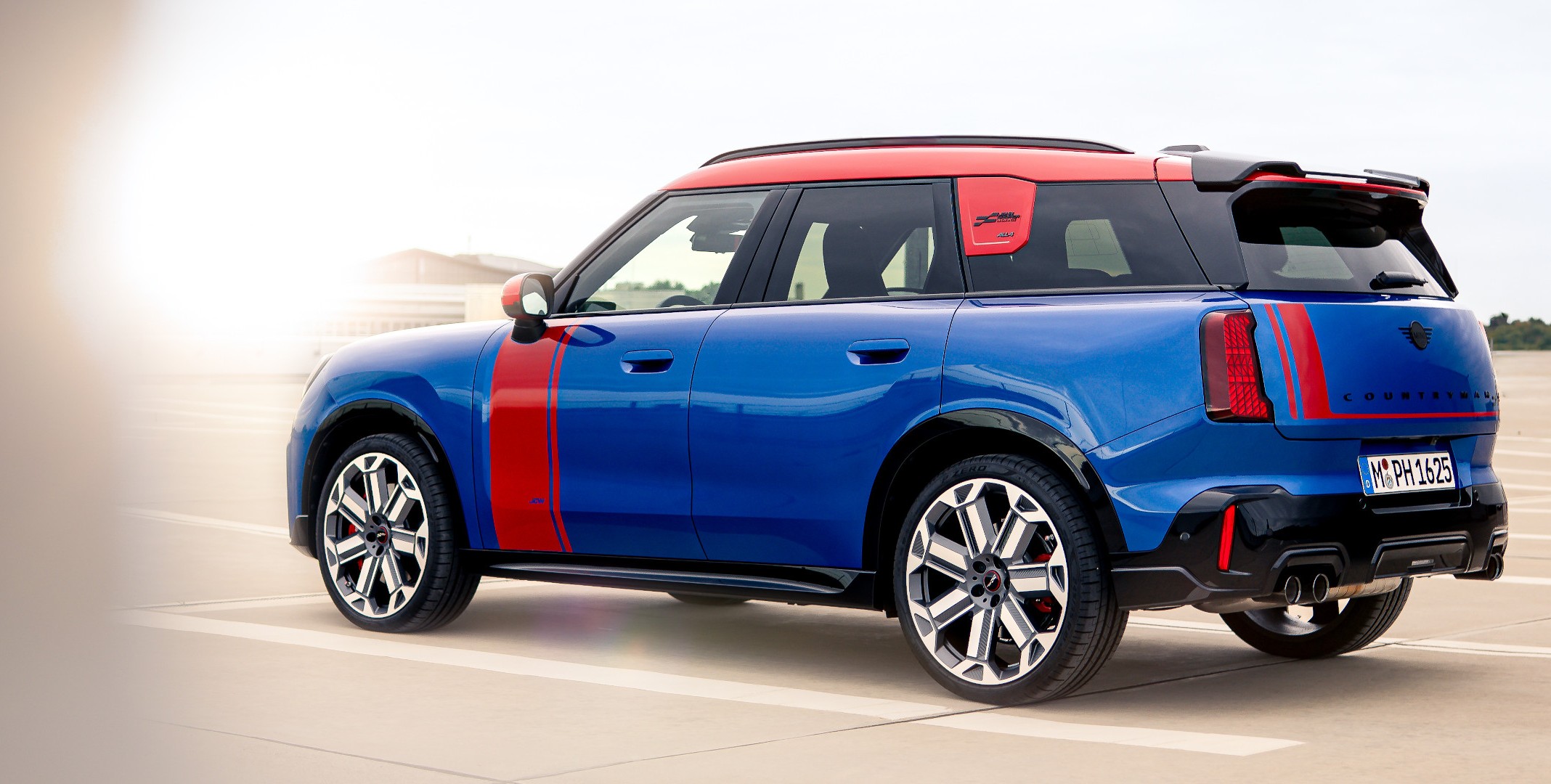 MINI Countryman in blazing blue mit JCW Folierung in chilli red, Seitenansicht.